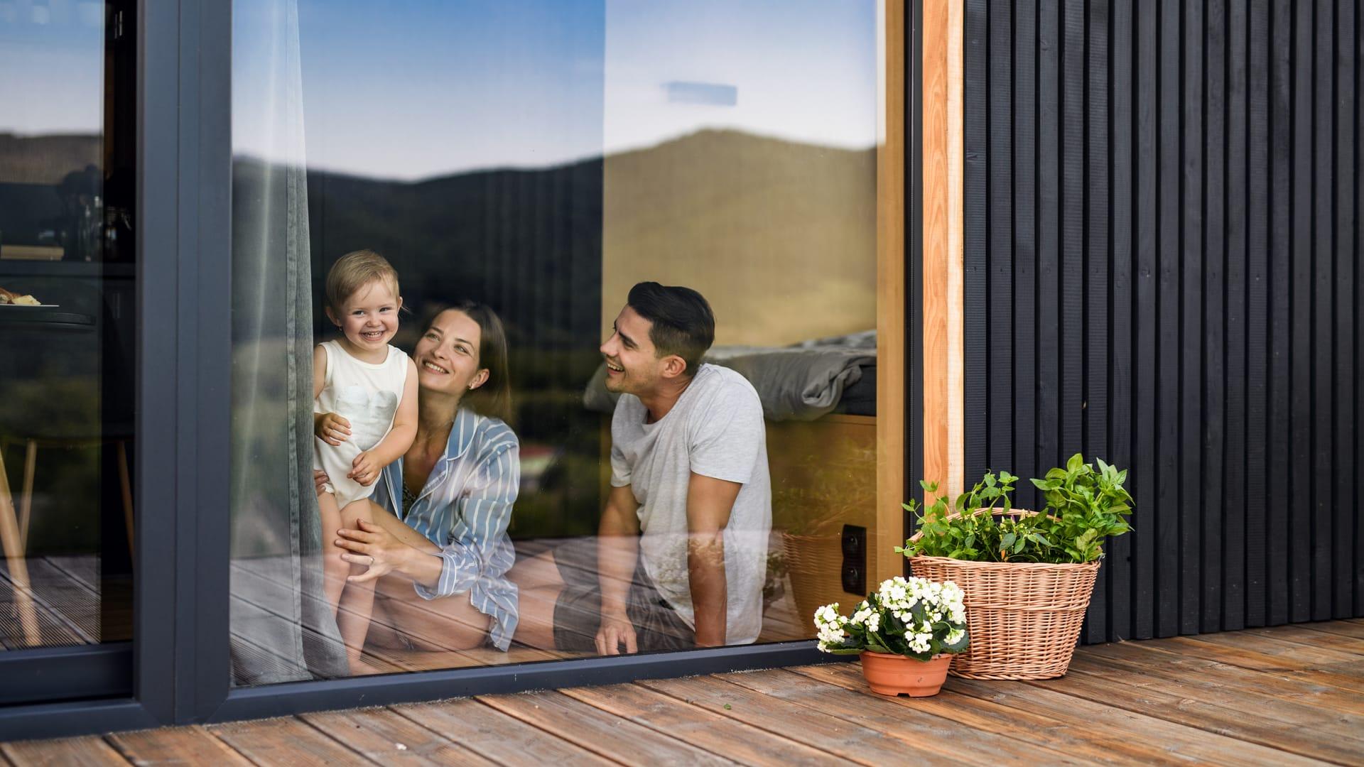 Parents with their young daughter looking out the window of their home